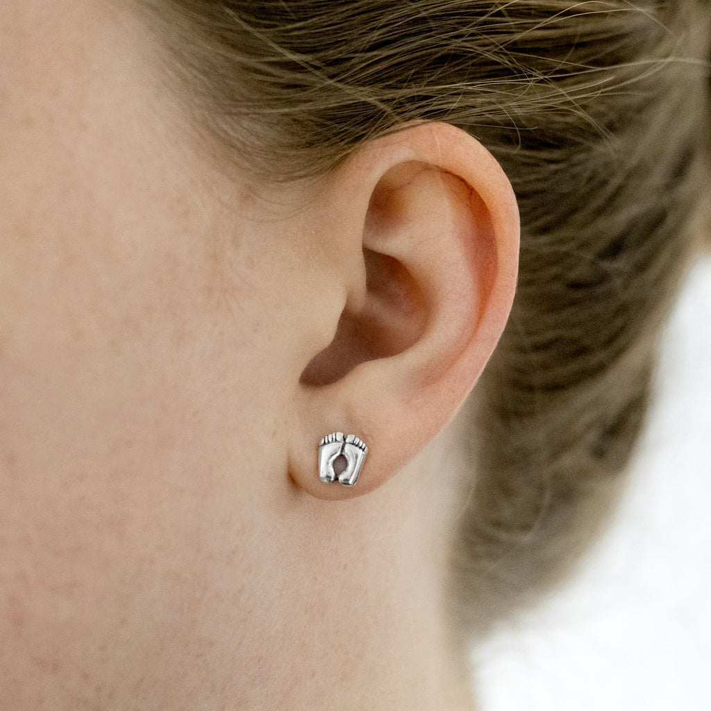 Footprint earrings on a model. Bright sterling silver studs.