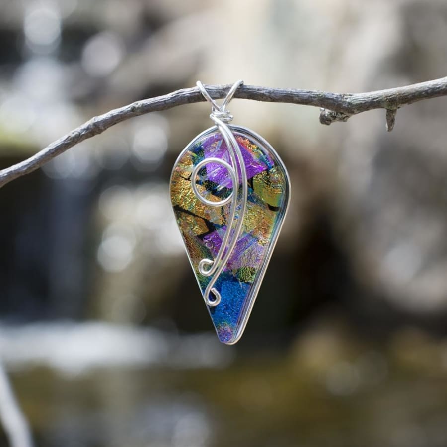 Dichroic glass pendant has shape of upside down tear drop. large end up, small end down.