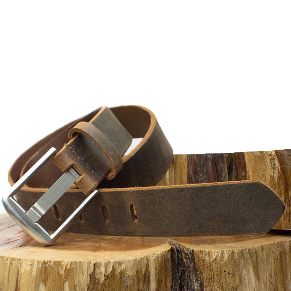 Titanium Wide Pin Distressed Leather Belt. Wooden platform. Rustic casual style, brown leather belt